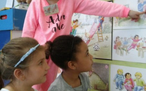 Dziewczynka wskazuje obrazek, dwie dziewczynki trzymają Zippiego