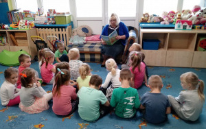 Pani Małgosia czyta przedszkolakom,dzieci siedzą na dywanie