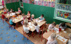 dzieci malują kundelki farbami przy stolikach