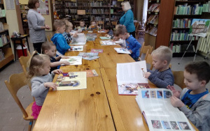 przedszkolaki przy stolikach oglądają ksiażki krajoznawcze