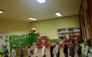 dzieci w czerwonych czapeczkach ustawione jedno za drugim na dywanie