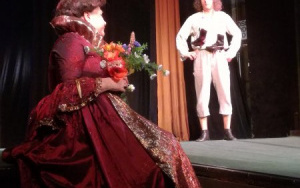 dama w długiej sukni z kwiatami i szewczyk Dratewka