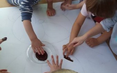 dzieci maluja misia brązową farbą za pomocą paluszków