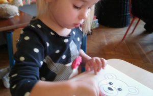 dziewczynka maluje paluszkie misia na kolor brązowy