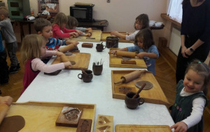 Dzieci wałkują piernikowe ciasto drewnianymi wałkami na stolnicach