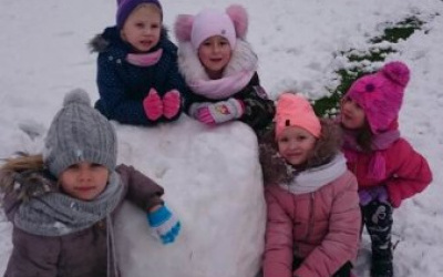 Dzieci pozują do zdjęcia,przykucają przy śniegowej kuli