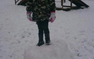 Dziewczynka stoi na ogromnej, śniegowej kuli