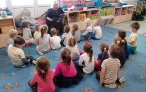 Pani Małgosia  czyta książkę, dzieci siedzą na dywanie