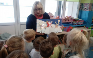 Pani Małgosia pokazuje ilustracjeę, bardzo zainteresowane dzieci stoją