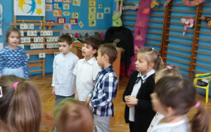 Dzieci stojąc w półkolu śpiewają piosenkę