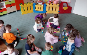dzieci budują domy z różnych, różnokolorowych klocków