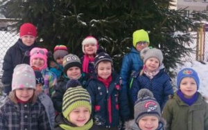 grupka dzieci na śniegu pod choinką