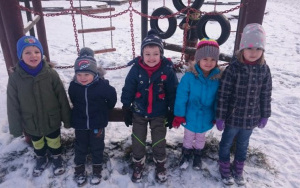 czworo dzieci w zimowych ubraniach na placu zabaw