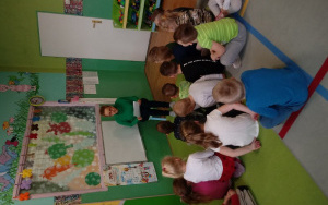 dzieci siedzą na dywanie i uważnie słuchają opowiadania