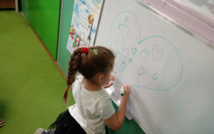 dziewczynka z warkoczem rysuje serce na tablicy
