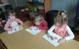 Dzieci kolorują serca przy stolikach na czerwono