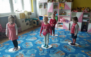 dzieci stoją na dywanie na papierowych sercach