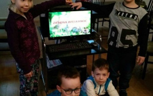 dzieci przykucają obok monitora komputera