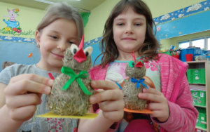 Dziewczynki prezentują swoje koguciki z sianka