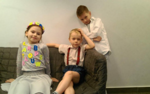 Julka i Mikołaj na kanapie, Paweł w białej koszuli wsparty o jej oparcie