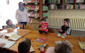 dziewczynka przy stole pokazuje dzieciom książeczkę Dzwoń pod 112