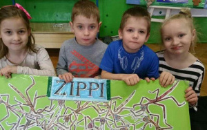 dzieci trzymają planszę z napisem Zippi,na niej patyczaki
