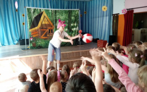aktor - świnka z lizakiem w dłoni gra z dziećmi z widowni w piłkę