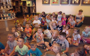Dzieci na dywaniesygnalizują chęć odpowiedzi na zadawane przez pana Jasia pytania, podnosząc palec do góry