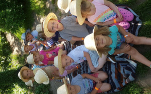 grupa maluszków w kapeluszach siedzi na kocu