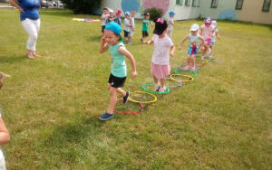 4. latki skaczą przez kolorowe obręcze ułożone na trawie
