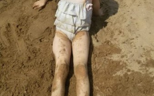 szczęśliwa dziewczynka ubrudzona w mokrym piasku