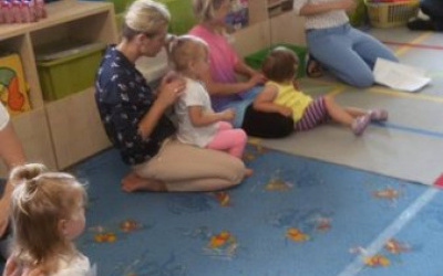 Dzieci siedzą na dywanie na kolanach rodziców