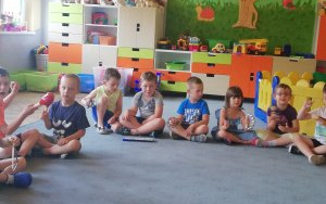 dzieci siedzą na dywanie,grają na instrumentach perkusyjnych