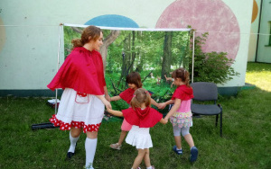 aktorka -  Czerwony Kapturek tańczy z trzema dziewczynkami w czerwonych kapturkach