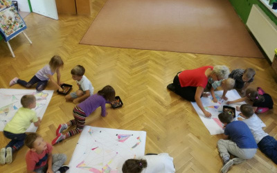 dzieci i ciocia Ania, w trzech grupach, pochyleni nad arkuszami papieru kolorują swoje mapy skarbu