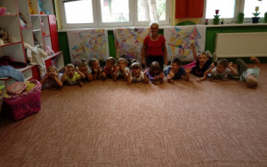 zadowolone z siebie dzieci z ciocią Anią siedzą na dywanie, za nimi trzy mapy skarbów