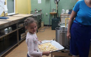 dziewczynkaw przedszkolnej kuchni z gotową do upieczenia pizzą