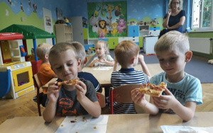 dzieci przy stolikach z apetytem zajadają gotową pizzę