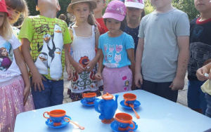 Dzieci przy stolikuna którym stoi niebieski dzbanek i filiżanki