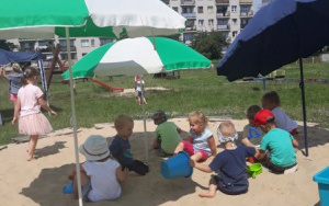 dzieci bawią się w piaskownicy, pod parasolami
