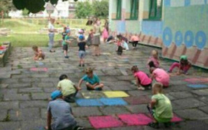 dzieci malują kredą płyty chodnikowe