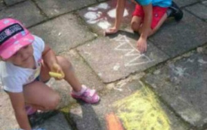 dzieci na kolanach rysują kredą na chodniku