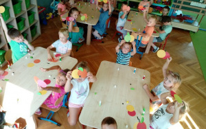 Dzieci przy stolikach robiąkolorowe wizytówki - jabłka, z kół