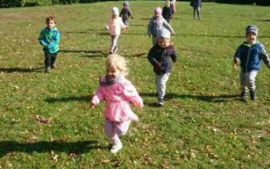 dzieci biegają po trawie wśród jesiennych liści
