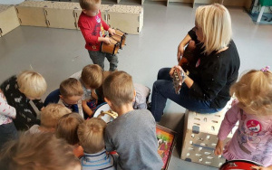 dzieci słuchają gry na gitarze,chłopiec trzyma bębenki
