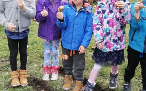 dzieci w jesiennych ubraniach stoją w ogrodzie, trzymają cebulki żonkili 