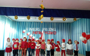 maluszki w czerwonych czapkach z polską flagą na scenie