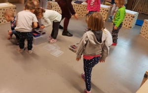 dzieci podchodzą po kredki rozłożone w przeźroczystych pudełkach na podłodze