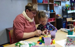 Pani Iwonka i dziewczynka przy stole z farbami malują gipsowe figurki misiów