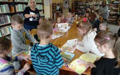 dzieci przy drewnianym stole z zainteresowaniem oglądają książki